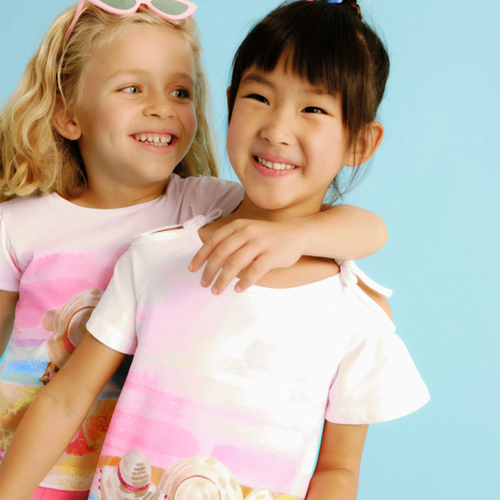 Dos niñas sonriendo con camisetas de verano de la marca Mayoral.